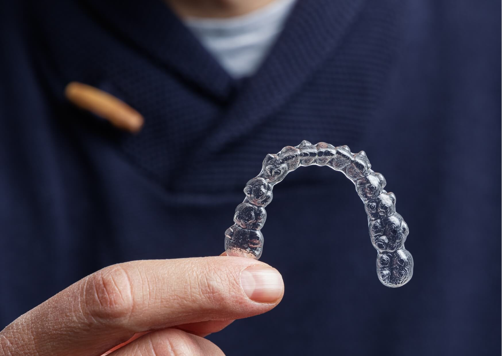 Custom clear nightguard held in hand, showing a dental appliance designed to prevent teeth grinding and reduce nighttime jaw pressure.